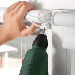Young man installing window screens indoors